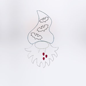May include: A white felt gnome with a pointy hat decorated with three black bats. The gnome has a red beard with three red dots.
