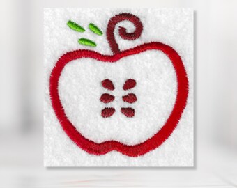 Puede incluir: Manzana roja bordada con un tallo y hojas verdes. La manzana está cortada por la mitad para mostrar las semillas en el interior.