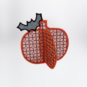 May include: A 3D orange pumpkin with a black bat on top. The pumpkin is made of a mesh fabric with a black and orange pattern.
