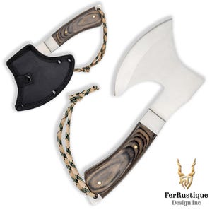 Könnte beinhalten: Zweiteiliges Axt-Set mit Holzgriffen mit dunklem Holzmaserungsmuster und Edelstahlklingen. Die Griffe sind mit Messingnieten befestigt. Eine Axt hat eine schwarze Scheide und beide haben ein Tarn-Lanyard.