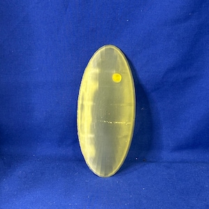 Op de afbeelding: Een lichtgroen ovaalvormig keramiek bord met een gele stip in het midden.