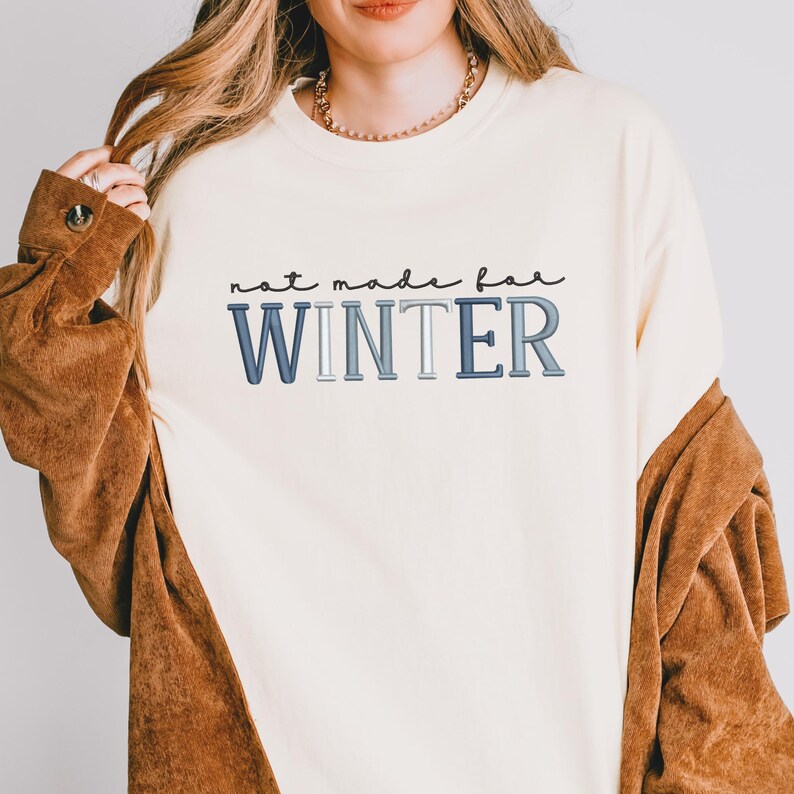 Puede incluir: Sudadera de color crema con el texto "not made for WINTER" en letras azules y grises. La sudadera es de estilo casual, adecuada para climas m&aacute;s fr&iacute;os. La imagen muestra a una persona usando la sudadera.