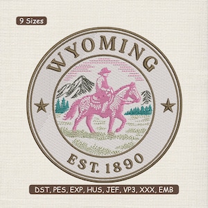 May include: Embroidered circular design featuring the word "WYOMING" above a pink silhouette of a rider on a horse. The design includes mountains, trees, and stars, with "EST. 1890" below. The design is surrounded by a brown border.