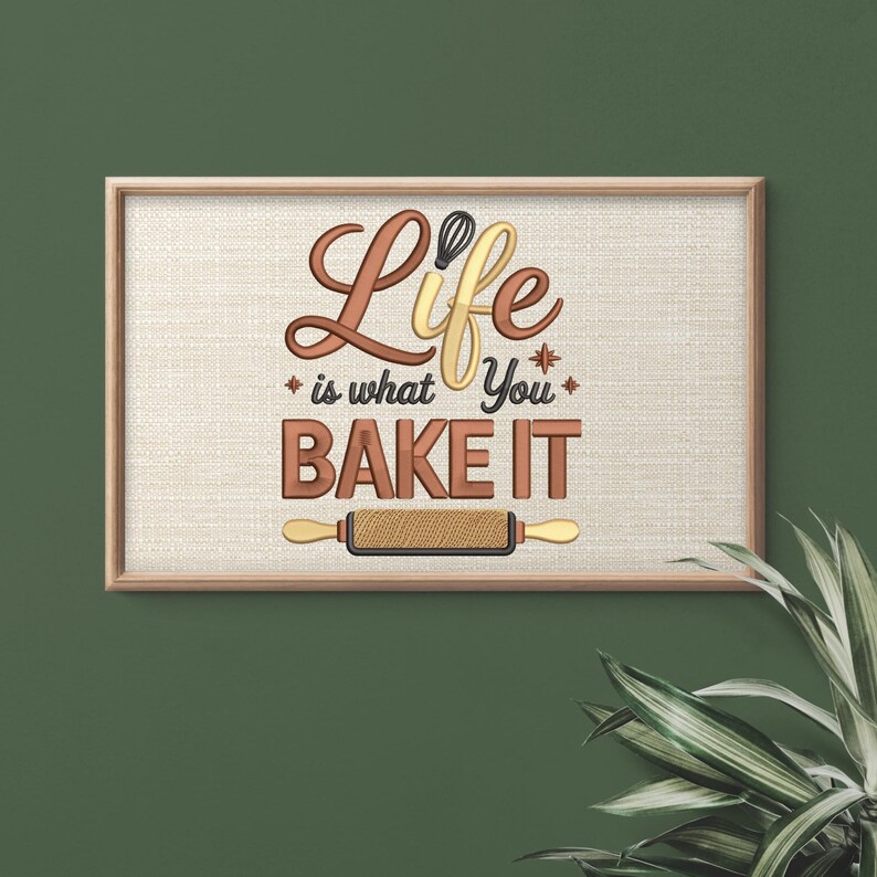 Pode incluir: Obra de arte emoldurada com o texto "Life is what you BAKE IT" em letras marrons e amarelas. A imagem inclui um batedor de arame e um rolo de massa sobre um fundo bege texturizado. A moldura &eacute; marrom claro.