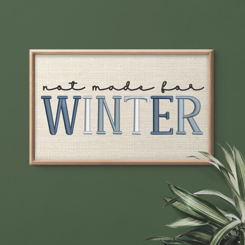 Puede incluir: Una obra de arte enmarcada con la frase "not made for WINTER". El texto est&aacute; en una mezcla de colores azul y blanco, con una fuente cursiva para "not made for" y una fuente de bloque para "WINTER". El fondo es de tela beige claro.