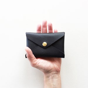 Hand holding black leather envelope style credit card case.