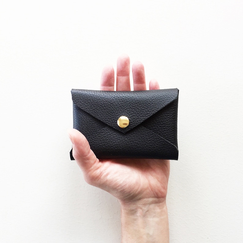 Hand holding black leather envelope style credit card case.