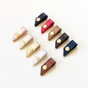 Set of ten leather cord keepers with button snap closures in a variety of colors.