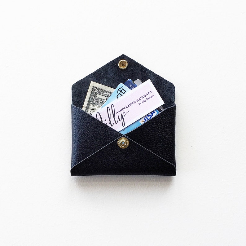 Black leather envelope style credit card case open with cash, business card and credit cards inside.