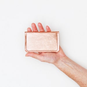 Hand holding a metallic leather credit card wallet.