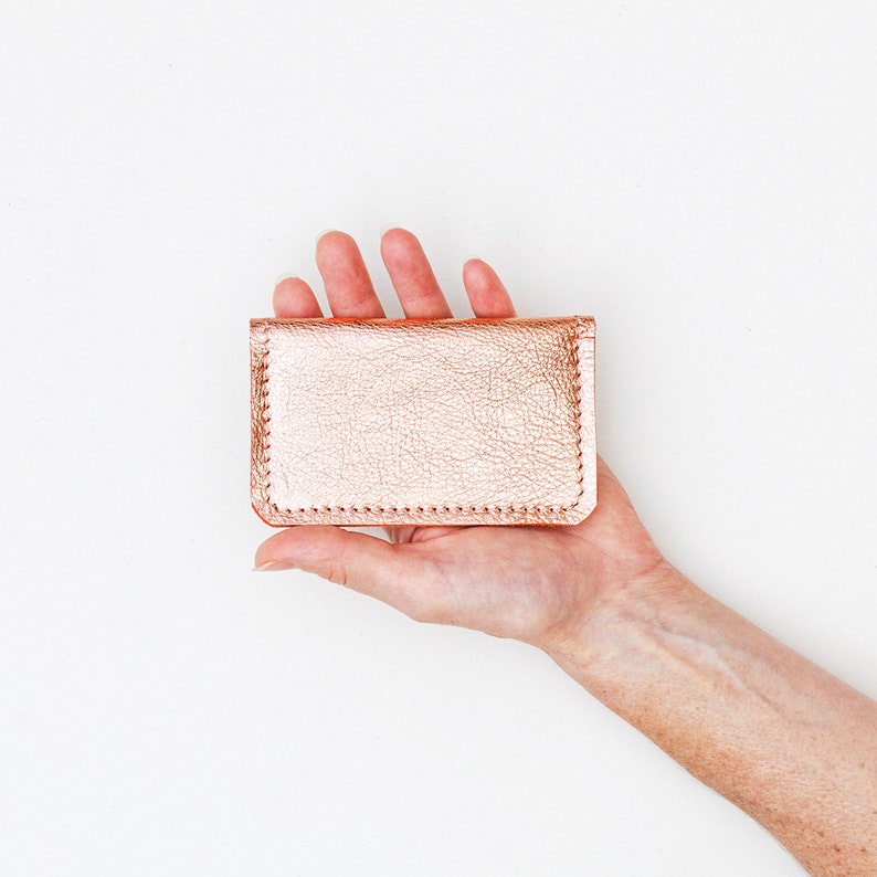 Hand holding a metallic leather credit card wallet.