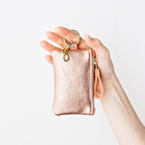 Hand holding metallic leather keychain zip wallet.