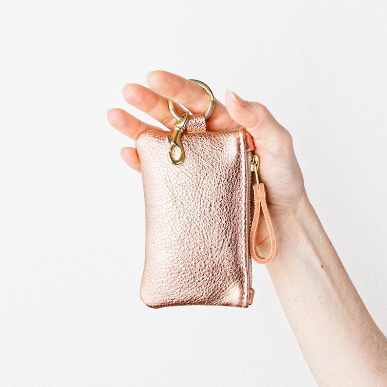 Hand holding metallic leather keychain zip wallet.