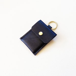 Angled top view of black leather keychain button snap credit card wallet.