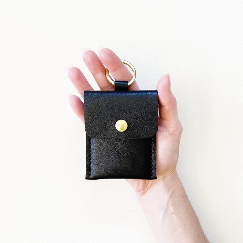 Hand holding black leather keychain button snap credit card wallet.
