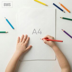 May include: A top-down view of a person's hands drawing on a white A4 paper with a red pencil. Several colored pencils, including blue, yellow, and green, are scattered around the paper on a white surface. The text "A4" is printed on the paper.
