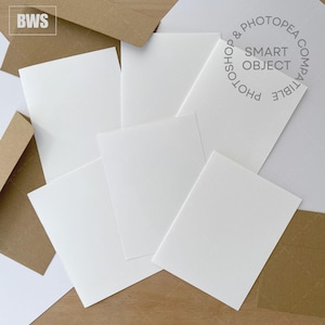 May include: An overhead shot shows several white rectangular cards and brown envelopes. The cards are arranged in a slightly overlapping pattern. The text "SMART OBJECT" and "PHOTOSHOP & PHOTOPEA COMPATIBLE" are visible on one card. The letters "BWS" are in the upper left corner.
