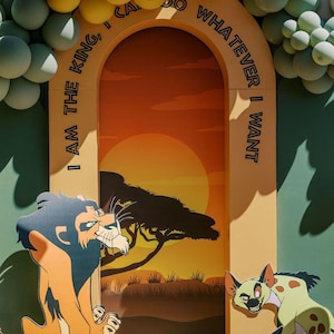 May include: A cardboard archway decorated with yellow and green balloons. The archway is decorated with the text "I am the king, I can do whatever I want".  The archway is set up in front of a backdrop depicting a sunset over a savanna with a lion and a hyena.