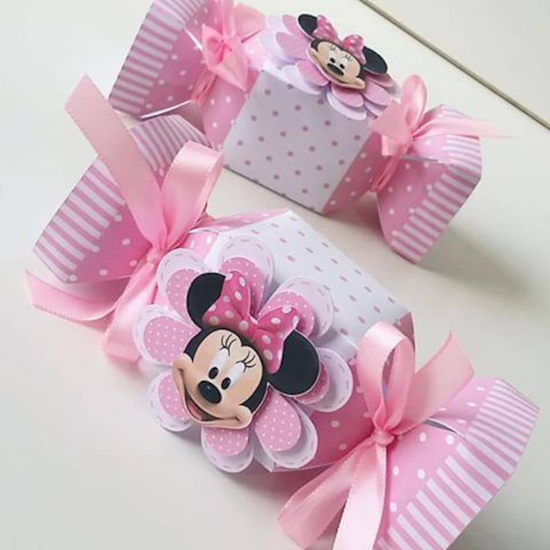 Pode incluir: Caixas de doces rosa e branco com um design de Minnie Mouse. As caixas s&atilde;o decoradas com bolinhas e listras. Cada caixa tem uma fita rosa amarrada ao redor.