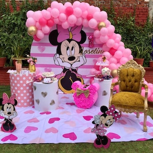Pode incluir: Um cen&aacute;rio de festa rosa e branco com tema Minnie Mouse com um arco de bal&otilde;es, um cen&aacute;rio listrado rosa e branco e um personagem de Minnie Mouse. O cen&aacute;rio &eacute; decorado com bolinhas rosa e brancas, cora&ccedil;&otilde;es e um n&uacute;mero um dourado. O texto "Joselin" est&aacute; escrito no cen&aacute;rio.