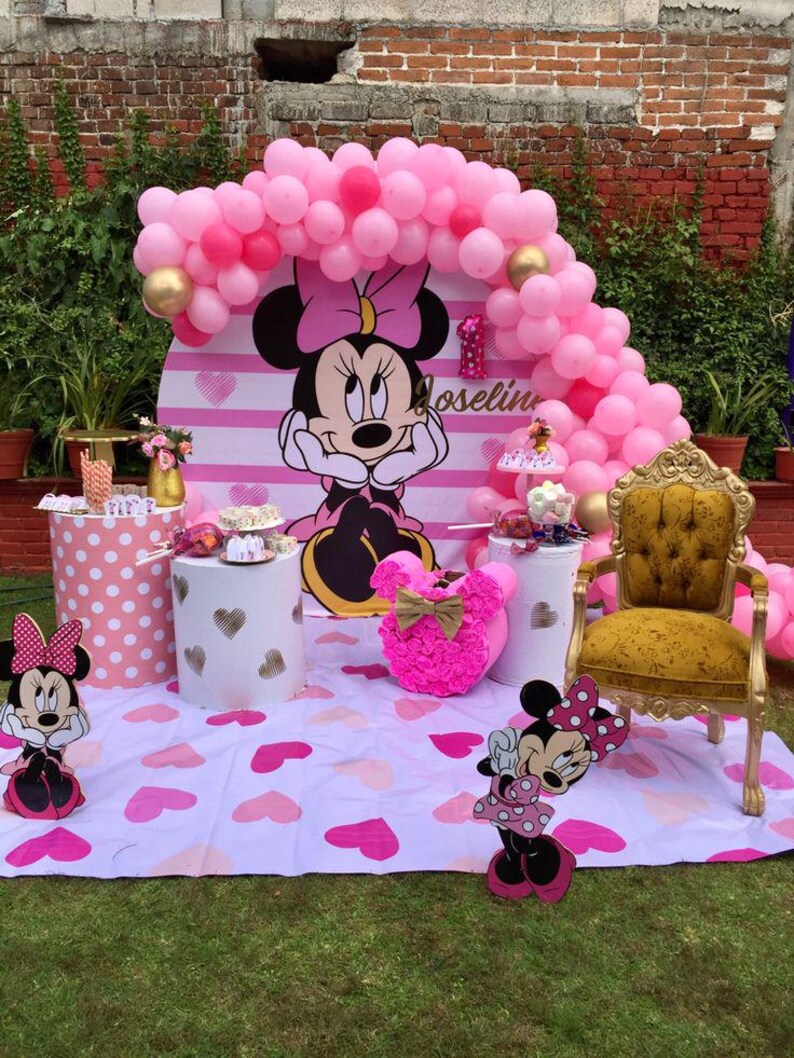 Pode incluir: Um cen&aacute;rio de festa rosa e branco com tema Minnie Mouse com um arco de bal&otilde;es, um cen&aacute;rio listrado rosa e branco e um personagem de Minnie Mouse. O cen&aacute;rio &eacute; decorado com bolinhas rosa e brancas, cora&ccedil;&otilde;es e um n&uacute;mero um dourado. O texto "Joselin" est&aacute; escrito no cen&aacute;rio.