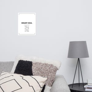 May include: A rectangular white wall art print featuring the black text BINARY SOUL centered at the top, followed by five rows of four-digit binary code numbers, all enclosed within a thin black rectangular border frame on a white background.
