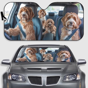May include: Car sunshade with a print of Labradoodle dogs in a car. The dogs are wearing seatbelts, giving the impression they are driving. The sunshade is designed to fit a car windscreen and protect the interior from sunlight.