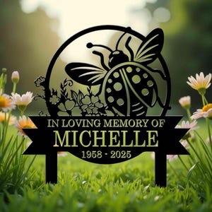 May include: Black metal garden stake with a ladybug design and the text "In loving memory of Michelle 1958 - 2025".
