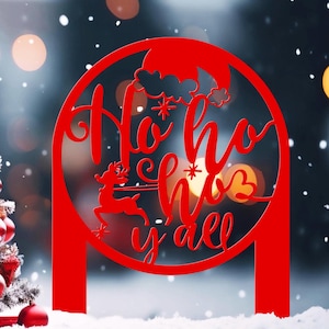 以下が含まれることがあります： 赤いクリスマスデコレーション。円形デザインの中に「Ho Ho Ho y'all」の文字。トナカイと雪の結晶のデザイン。雪の背景にぼやけたボケ効果があります。