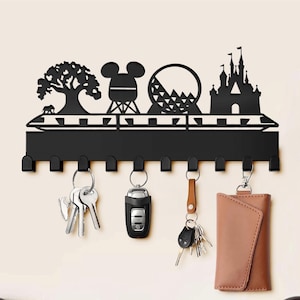 May include: Black metal key holder with a silhouette of a theme park, including a castle, a roller coaster, a tree, and Mickey Mouse's head. The key holder has 10 hooks and is mounted on a white wall. Keys and a wallet are hanging on the hooks.