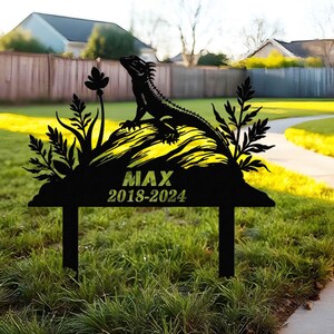 May include: Black metal garden memorial with a lizard silhouette, foliage, and the text "MAX 2018-2024".