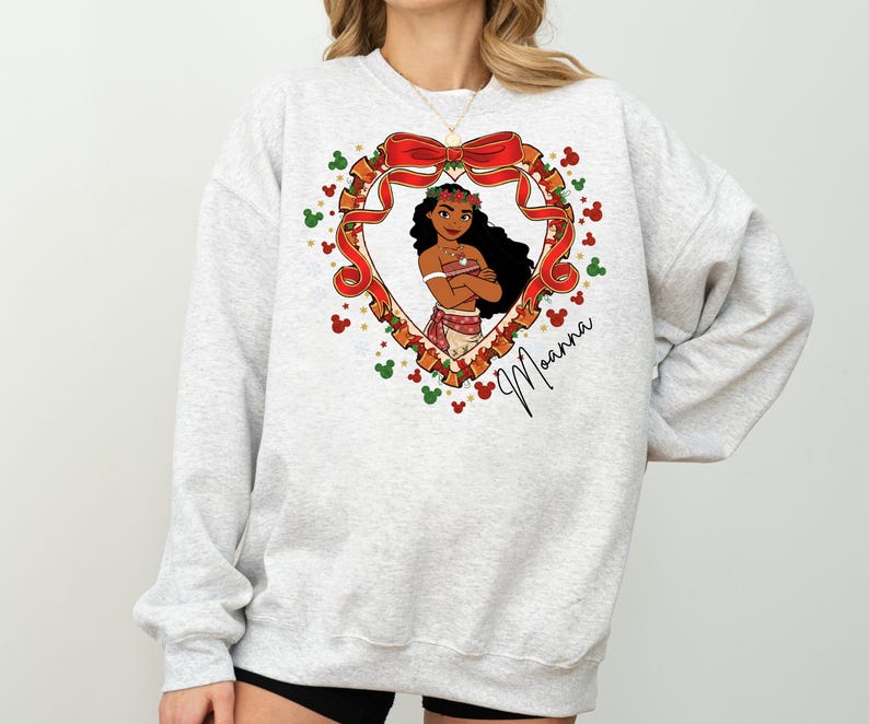 A woman wearing a gray sweatshirt with a heart-shaped graphic featuring a cartoon character and a bow.