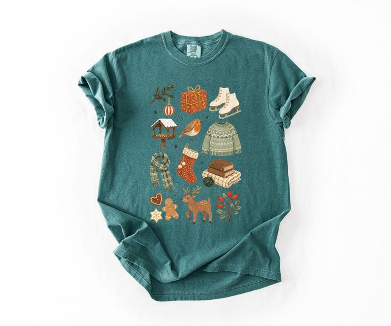 A green t-shirt with a collage of various Christmas-themed items and decorations, including a pair of skis, a gift box, a gingerbread man, a reindeer, and other festive symbols.