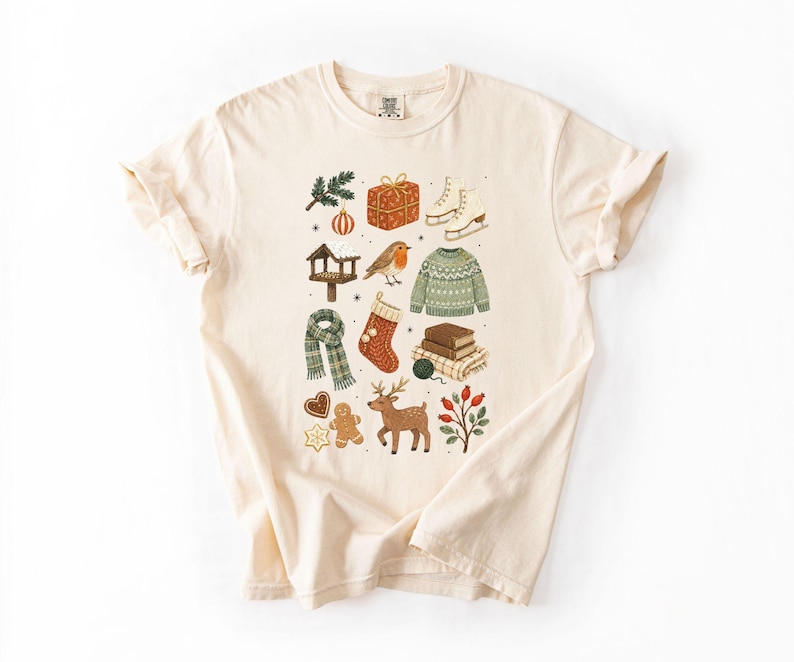 A white t-shirt with a graphic design featuring various Christmas-themed items such as a snowman, presents, a gingerbread man, and a reindeer.