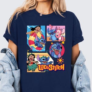 May include: A navy blue short-sleeve t-shirt featuring a graphic print of Lilo and Stitch characters in various scenes, including swimming, dancing, and heart motifs, with the text Lilo & Stitch printed in yellow at the bottom of the design.