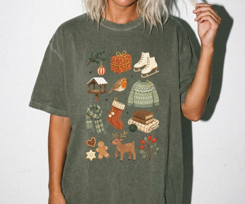 A person wearing a green t-shirt with a collage of various Christmas-themed illustrations, including a snowman, presents, skis, a bird, a reindeer, and other festive elements.