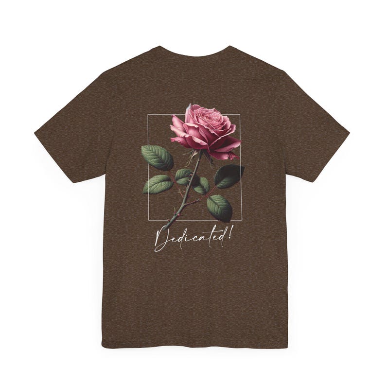 May include: A brown t-shirt with a pink rose graphic and the text "Dedicated!" printed on the back.