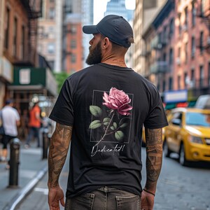 May include: A black t-shirt with a pink rose graphic and the text "Dedicated!" printed on the back.
