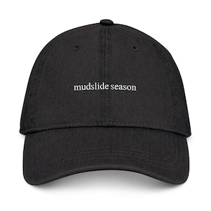 Pode incluir: Boné de beisebol preto com a frase "mudslide season" bordada em branco. O boné tem uma viseira curva e um design clássico de seis painéis. Feito de um material resistente, é ideal para uso diário.