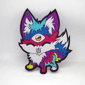 May include: A colorful, cartoon-style fox with a single large eye and a tongue sticking out. The fox is made of a white fabric with a psychedelic pattern of pink, blue, purple, and yellow.