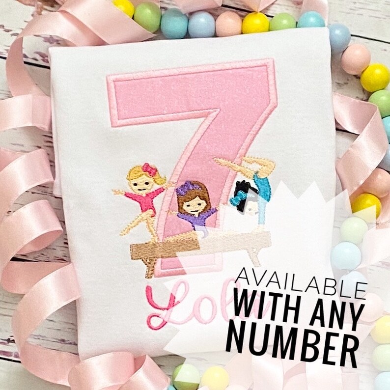 May include: A pink embroidered number 7 with three girls doing gymnastics on a balance beam. The text "Available with any number" is below the image.