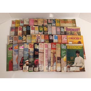 May include: A large collection of vintage Workbasket magazines arranged in rows, featuring various colorful covers with text such as The Workbasket, Quick & Easy Crochet, and diverse craft project illustrations including crochet, cross-stitch, and seasonal themes.