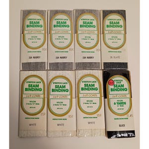 May include: Eight packages of J. & P. Coats stretch lace seam binding in various colors. Seven packages contain 3 yards of 0.5-inch wide nylon lace in gray, slate, and white. One package contains 6 yards of 0.5-inch wide black nylon stretch lace.