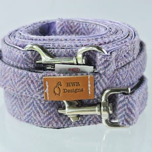 Könnte beinhalten: Eine Hunde-Leine aus violett-rosa Tweed mit silbernen Verschlüssen und einem braunen Lederanhänger mit der Aufschrift "HWR Designs".