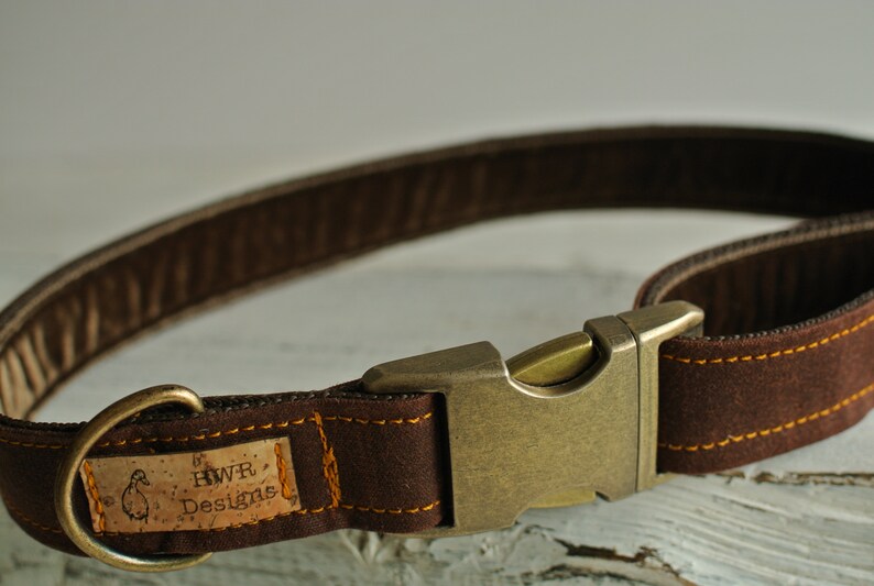 May include: Brown leather dog collar with a brass buckle and a cork tag that reads "HWR Designs".