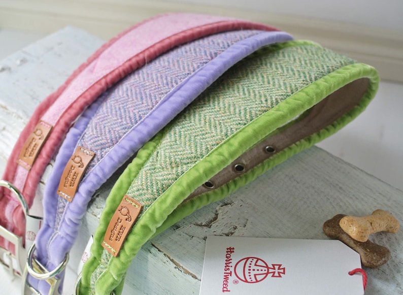 May include: Three dog collars in different colors: pink, lavender, and green. Each collar has a herringbone pattern and a contrasting colored velvet trim. The collars are made of tweed and have a leather label with the text "How's Tweed" on them.