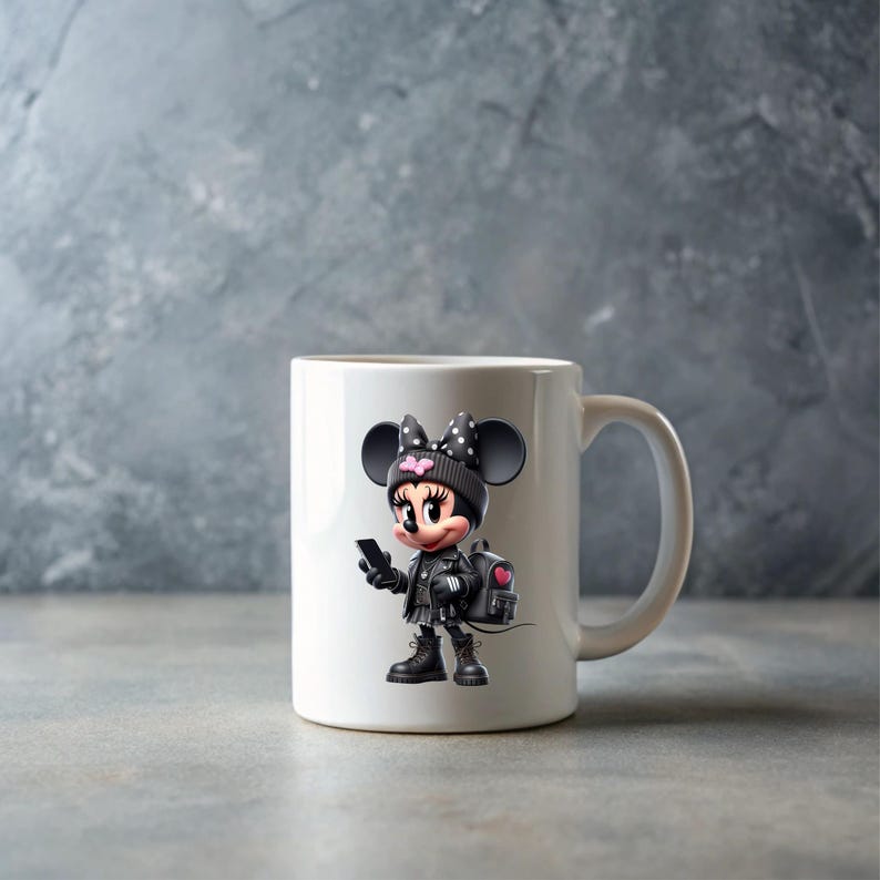 Peut inclure: Tasse en c&eacute;ramique blanche avec un dessin de Minnie Mouse en tenue noire, tenant un t&eacute;l&eacute;phone. Le design comprend un sac &agrave; dos noir avec un c&oelig;ur rose, un chapeau noir avec un n&oelig;ud et des bottes noires. La tasse a une anse blanche.