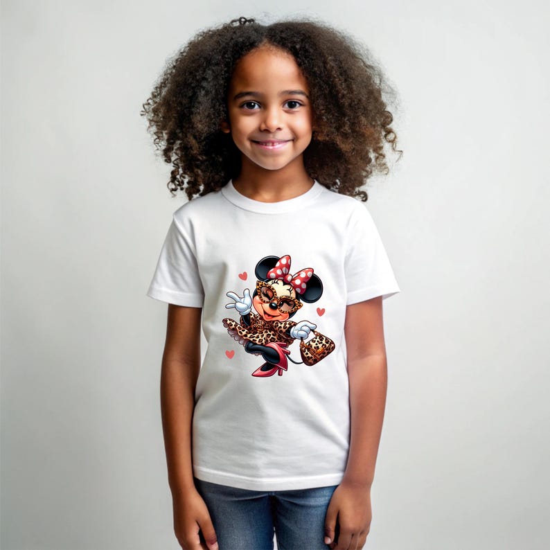 May include: White t-shirt featuring a cartoon Minnie Mouse in a leopard print outfit, sunglasses, and a red bow. The design includes small pink hearts. The shirt is worn by a young girl.