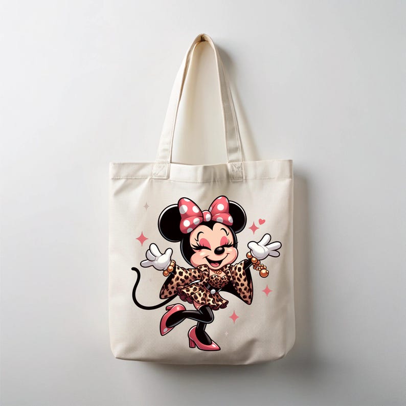 May include: A cream-colored tote bag featuring a cartoon illustration of Minnie Mouse. Minnie is wearing a leopard print outfit, pink heels, and a pink polka dot bow. The design includes pink star accents.
