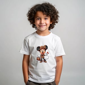 May include: A white t-shirt featuring a cartoon Minnie Mouse character in a leopard print outfit, including a hat, jacket, and purse. The character is holding a red flower. The child is smiling.